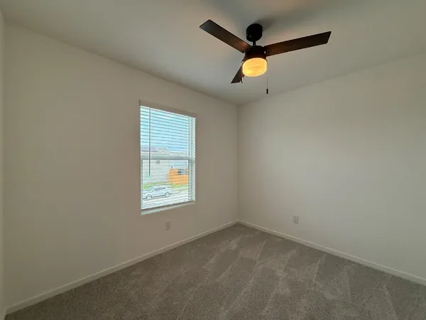 en empty room with ceiling fan and window