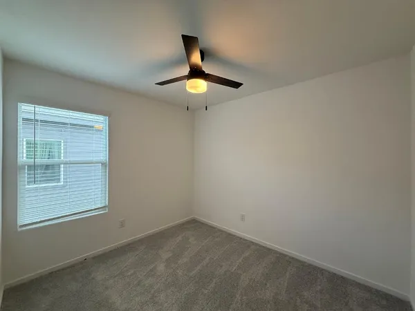 an empty room with a ceiling fan and window