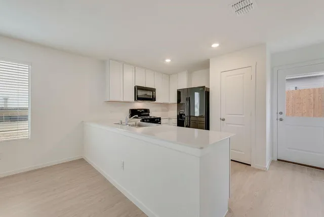 a view of kitchen with stainless steel appliances cabinets and a refrigerator
