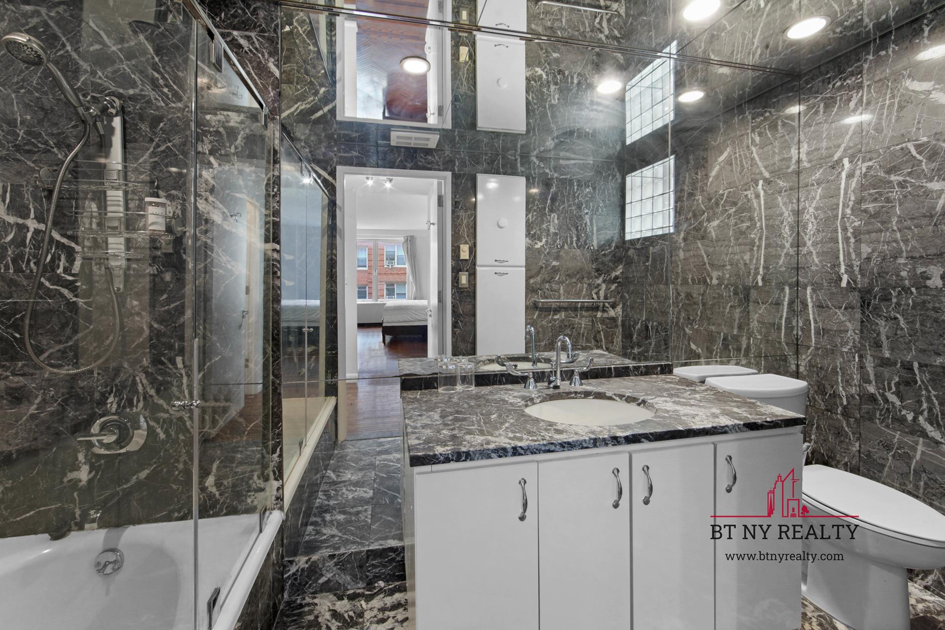 216-218 East 47th Street, Unit 4A Manhattan, NY 10017 - Photo 7 of 10 a bathroom with a granite countertop sink a toilet and bathtub