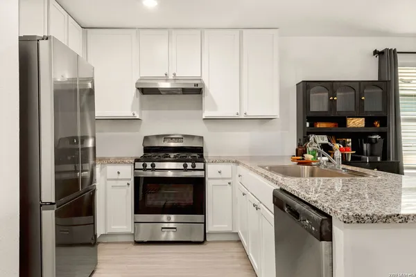 a kitchen with stainless steel appliances granite countertop a refrigerator a stove a sink and a microwave
