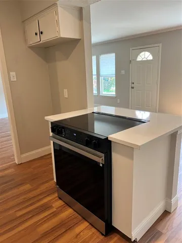 a kitchen with granite countertop a stove and a wooden floor