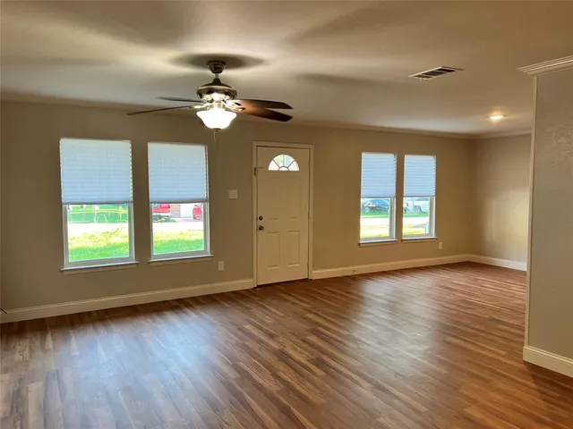 a view of an empty room with wooden floor and a window