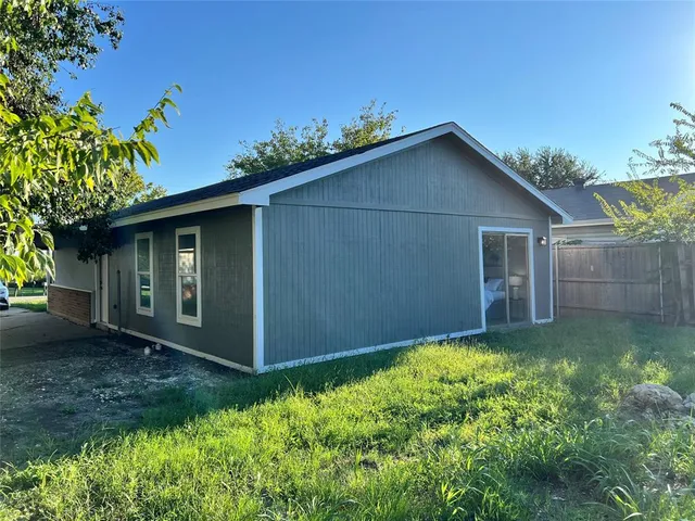 a backyard of a house with plants and large tree