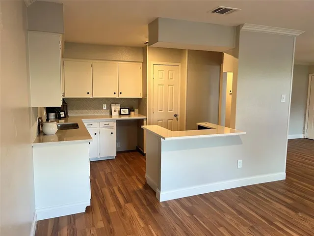a kitchen with wooden floors and white walls
