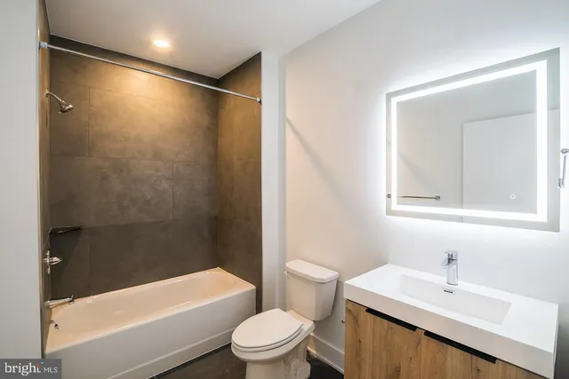 a bathroom with a bathtub shower sink vanity and toilet