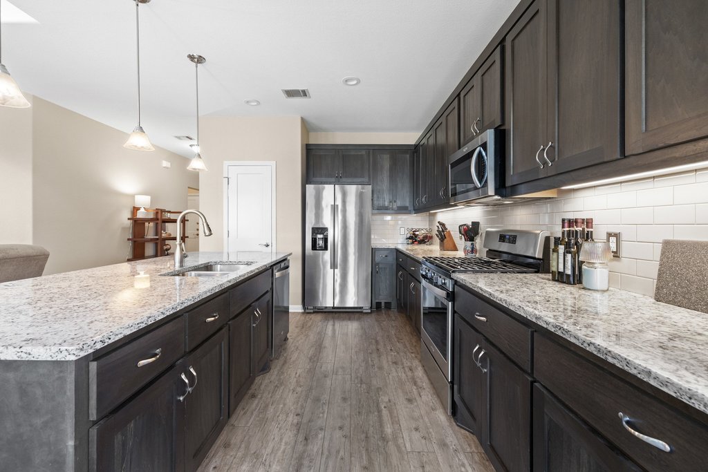1720 Prather Street Taylor, TX 76574 - Photo 12 of 34 a kitchen with stainless steel appliances granite countertop a sink a stove and a wooden floors