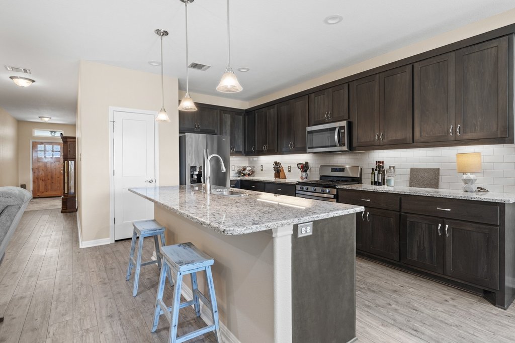 1720 Prather Street Taylor, TX 76574 - Photo 13 of 34 a kitchen with stainless steel appliances granite countertop wooden cabinets a sink a stove a refrigerator and island with wooden floor