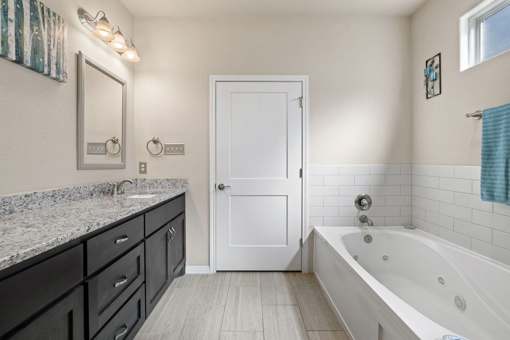 1720 Prather Street Taylor, TX 76574 - Photo 21 of 34 a bathroom with a granite countertop bathtub a sink and a mirror