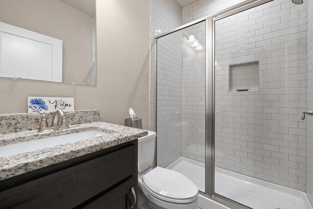 1720 Prather Street Taylor, TX 76574 - Photo 23 of 34 a bathroom with a granite countertop sink toilet and shower