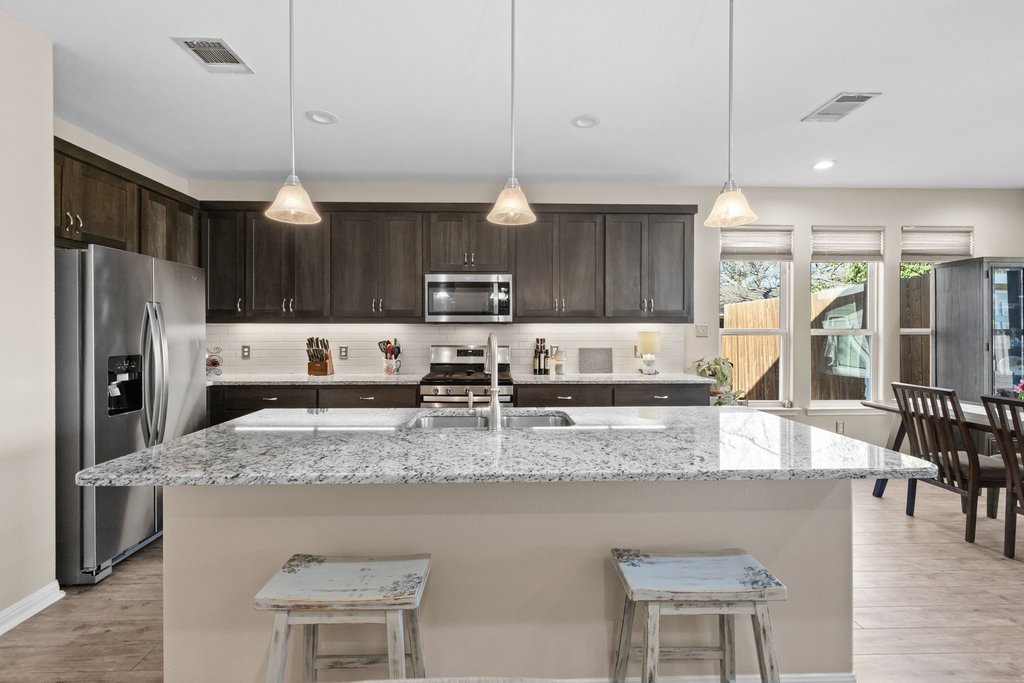 1720 Prather Street Taylor, TX 76574 - Photo 7 of 34 a kitchen with stainless steel appliances granite countertop a sink refrigerator and cabinets