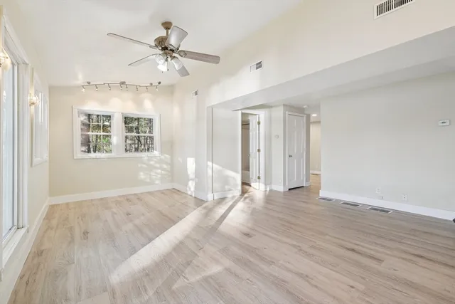 a view of an empty room with a window and wooden floor
