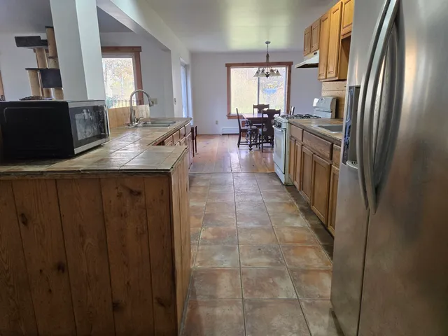a kitchen with kitchen island granite countertop a sink and refrigerator