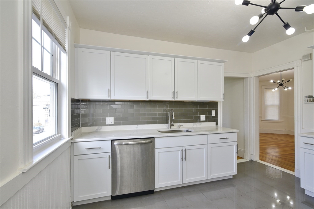 24 Rector Road, Unit 2 Boston, MA 02126 - Photo 3 of 17 a kitchen with a sink dishwasher and white cabinets with wooden floor