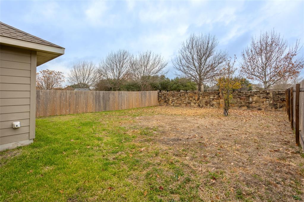 615 Stampede Road San Marcos, TX 78666 - Photo 24 of 26 A generous backyard offers both a privacy fence and a natural stone wall for varied outdoor enjoyment.