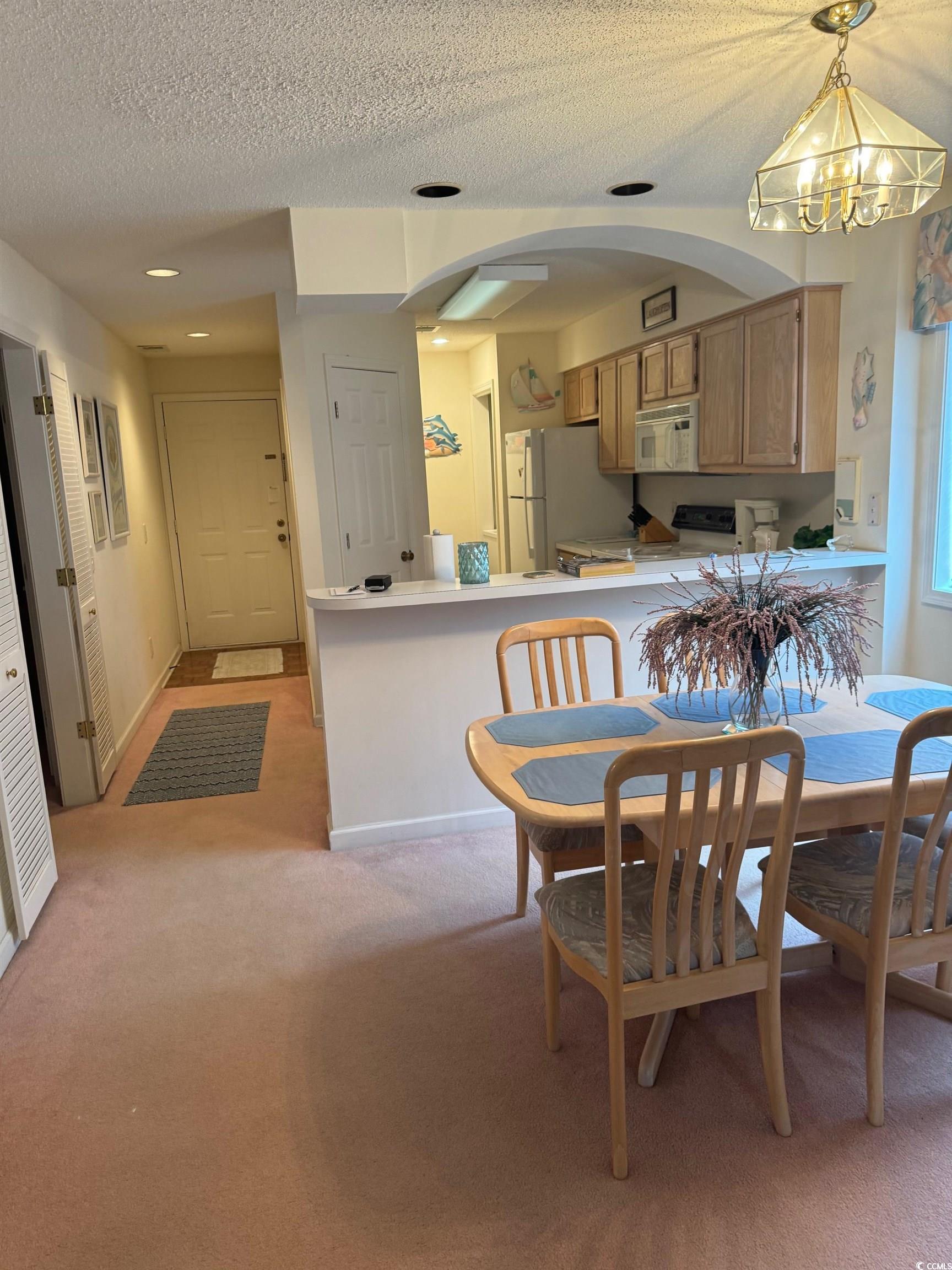 1900 Duffy Street, Unit J4 North Myrtle Beach, SC 29582 - Photo 11 of 22 Dining space with light colored carpet, a textured ceiling, and a chandelier