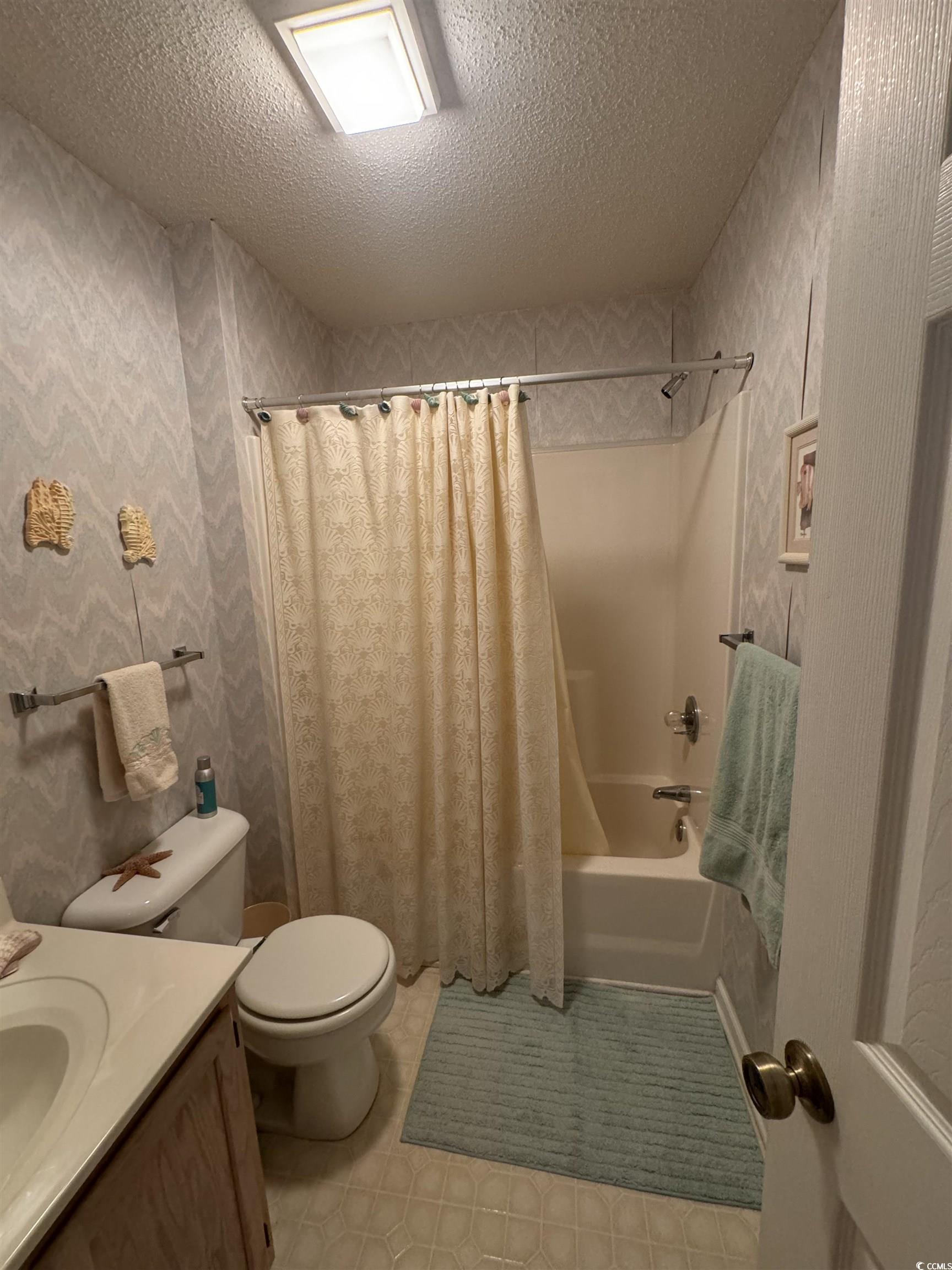 1900 Duffy Street, Unit J4 North Myrtle Beach, SC 29582 - Photo 16 of 22 Full bathroom with shower / bathtub combination with curtain, a textured ceiling, vanity, light tile patterned flooring, and wallpapered walls