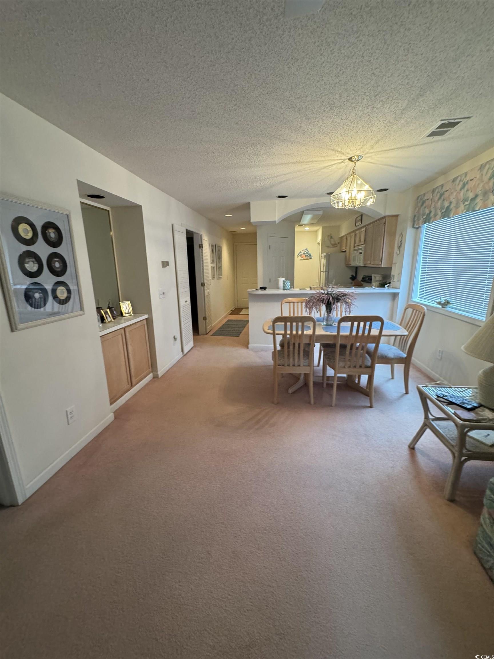1900 Duffy Street, Unit J4 North Myrtle Beach, SC 29582 - Photo 3 of 22 Dining space with a textured ceiling, light colored carpet, arched walkways, and a chandelier