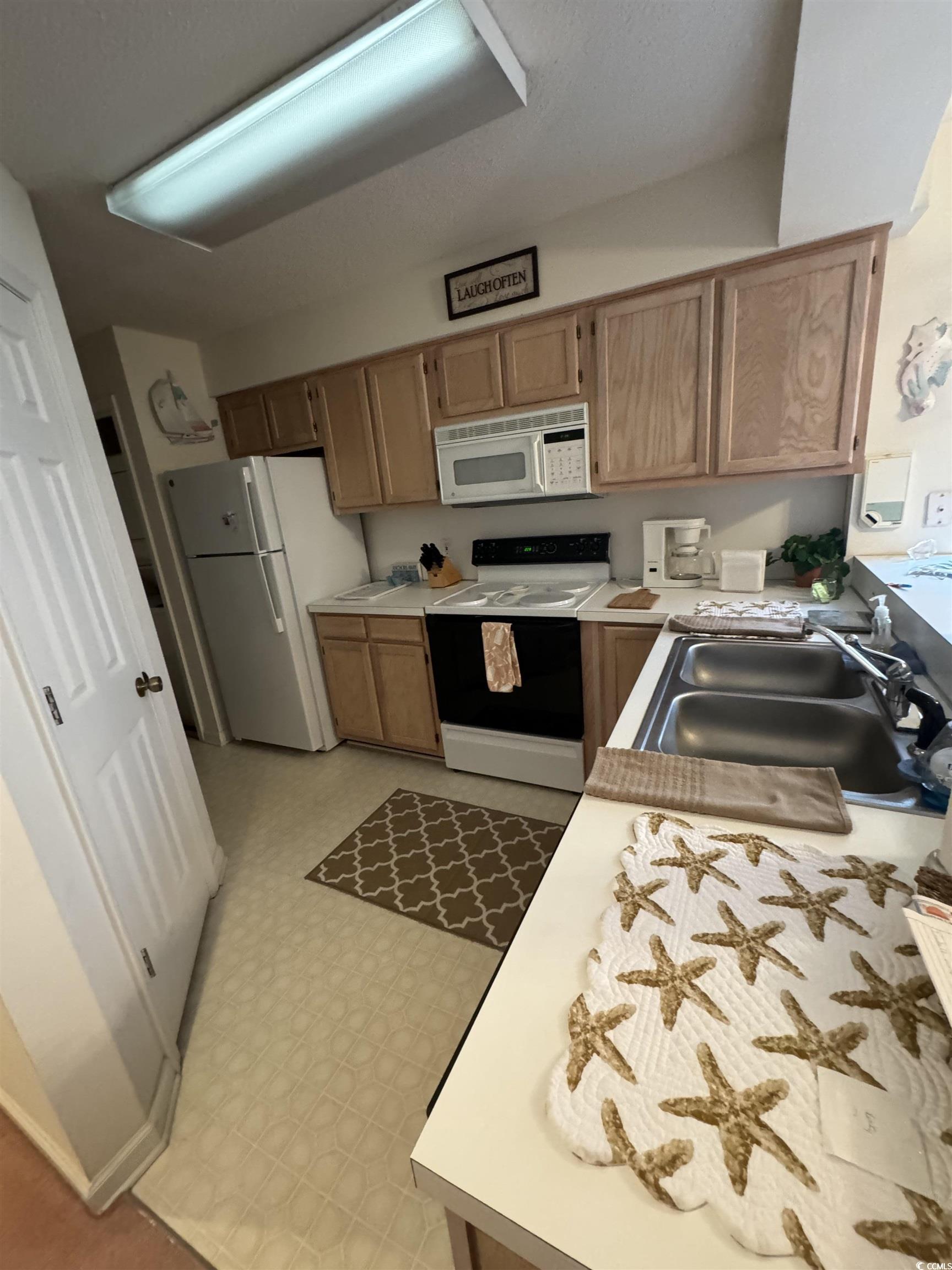 1900 Duffy Street, Unit J4 North Myrtle Beach, SC 29582 - Photo 4 of 22 Kitchen featuring light countertops, white appliances, light brown cabinetry, and light flooring