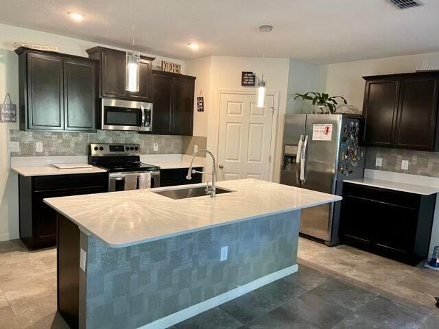 1117 Southwest Goodman Avenue Port St. Lucie, FL 34953 - Photo 5 of 18 a large kitchen with stainless steel appliances kitchen island granite countertop a refrigerator stove a sink and dishwasher