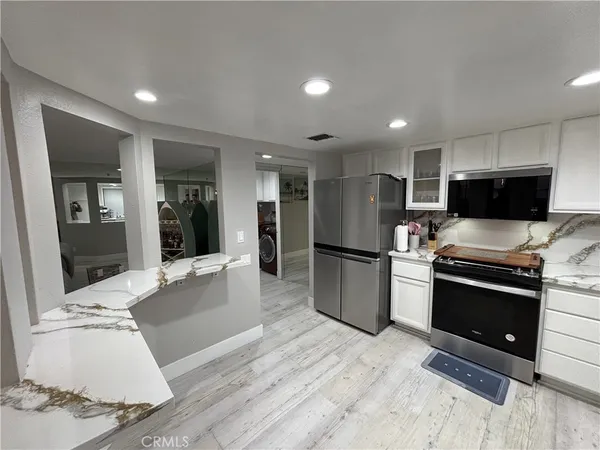 a large kitchen with stainless steel appliances kitchen island granite countertop a refrigerator and a stove top oven