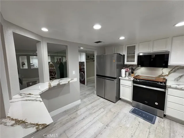 a large kitchen with stainless steel appliances kitchen island granite countertop a refrigerator and a stove top oven