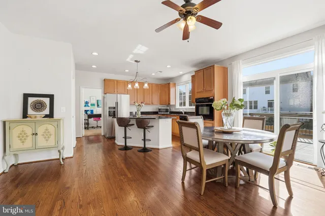 a kitchen with stainless steel appliances granite countertop a refrigerator a stove a sink a dining table and chairs with wooden floor