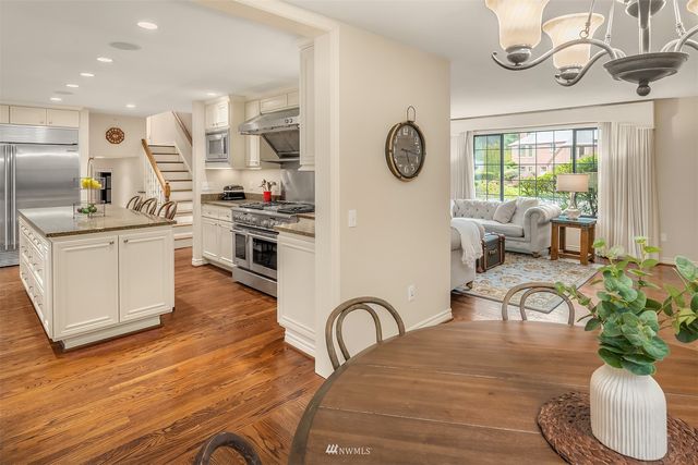 a kitchen with stainless steel appliances granite countertop a stove a sink dishwasher and white cabinets with wooden floor