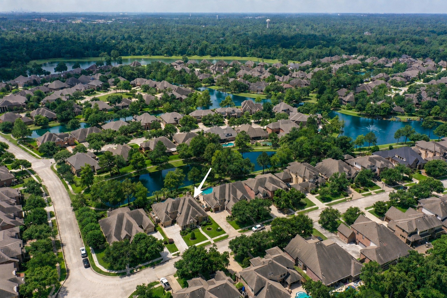 2407 Hendricks Lakes Drive Spring, TX 77388 - Photo 44 of 50 Marked from above, 2407 Hendricks Lakes Drive sits within the gated Lakes of Cypress Forest setting, surrounded by water, winding paths, fountains, and established greenery. This view helps place the home’s poolside backyard within the larger water-front lifestyle, where the backyard connects naturally to the trails and scenic community spaces just beyond.
