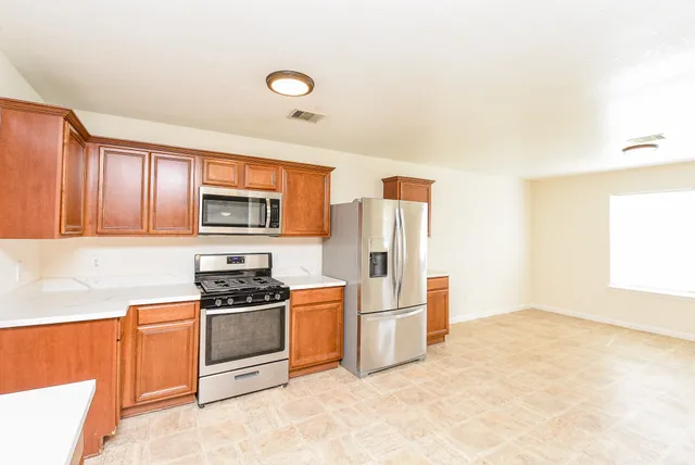 a kitchen with stainless steel appliances granite countertop a stove a refrigerator and a sink with cabinets