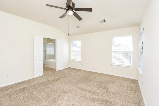 a view of a big room with a ceiling fan and windows in a room
