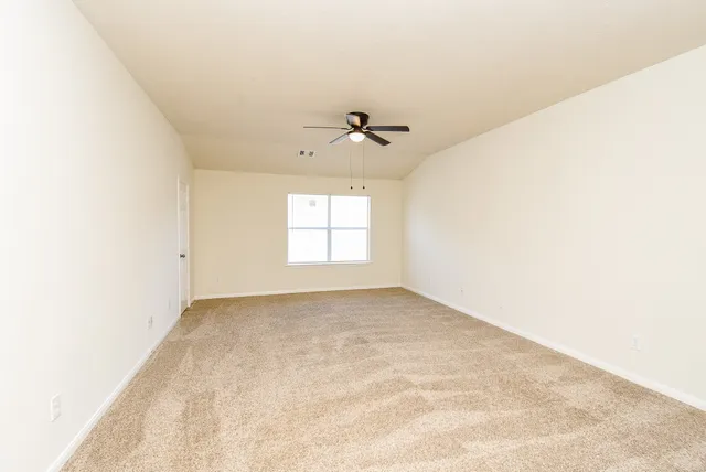 an empty room with windows and ceiling fan