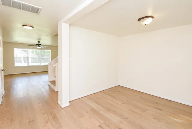 a view of empty room with wooden floor and fan