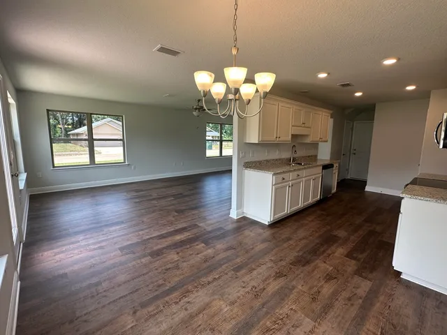 a kitchen with stainless steel appliances granite countertop wooden floors and a view of living room