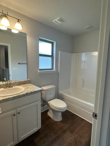 a bathroom with a granite countertop toilet a sink and a mirror
