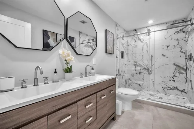 a bathroom with a double vanity sink mirror and toilet