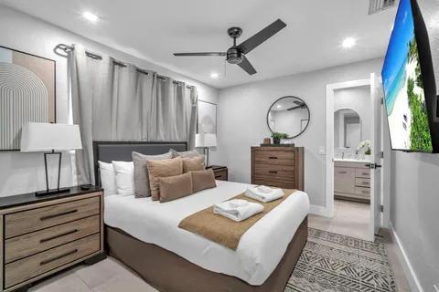 a bedroom with a bed a mirror on dresser and a chandelier