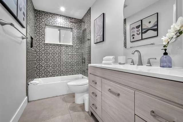 a bathroom with a toilet a sink a mirror a window and vanity