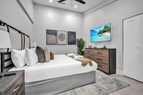 a bedroom with a bed and dresser with wooden floor