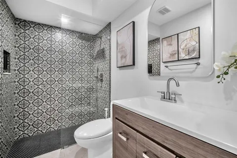 a bathroom with a granite countertop toilet sink and mirror