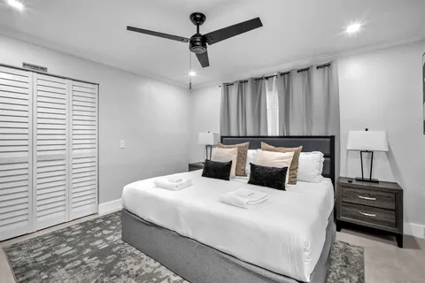 a bedroom with a bed a ceiling fan and a dresser