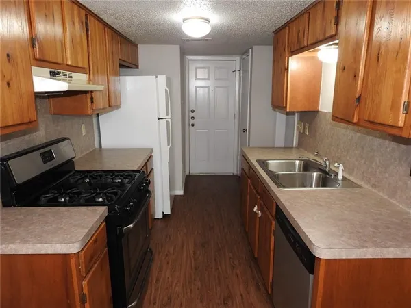 a kitchen with granite countertop a sink stove and refrigerator