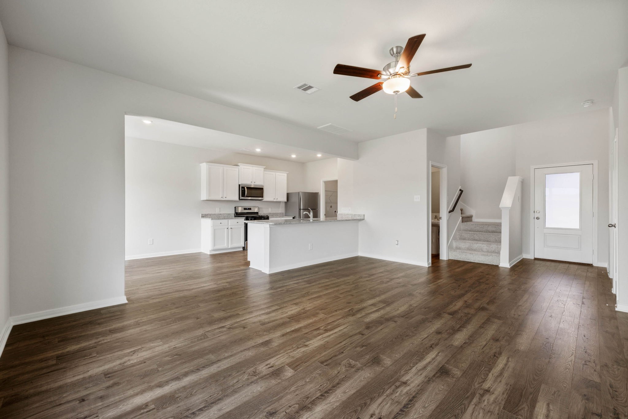 10414 Red Cardinal Drive Cleveland, TX 77328 - Photo 1 of 12 a view of an empty room with wooden floor and a kitchen
