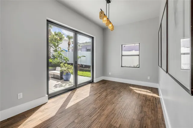 a view of an empty room with wooden floor and a bathroom