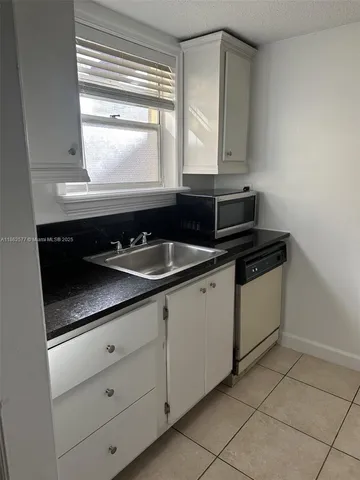 a kitchen with granite countertop white cabinets and black appliances