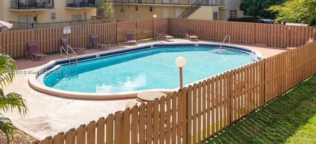 a view of a backyard with a small pool and wooden fence