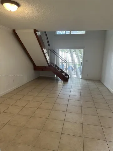 a view of an empty room and staircase with a rug