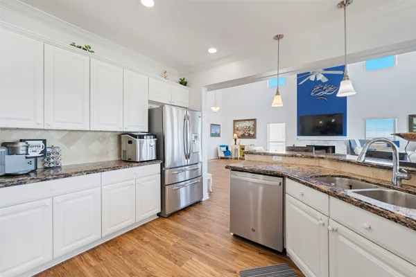 a kitchen with stainless steel appliances granite countertop a stove a sink and a wooden floor