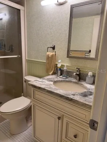 a bathroom with a granite countertop toilet sink and mirror