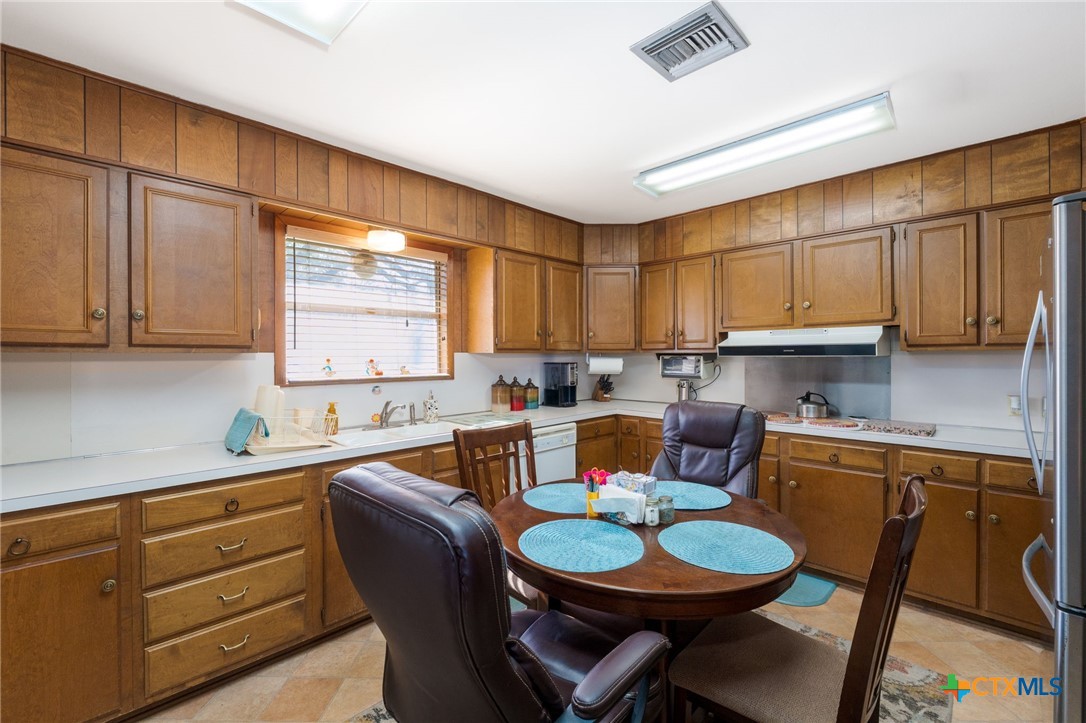 1003 North Ridge Street Lampasas, TX 76550 - Photo 9 of 44 a kitchen with a sink a stove cabinets dining table and chairs